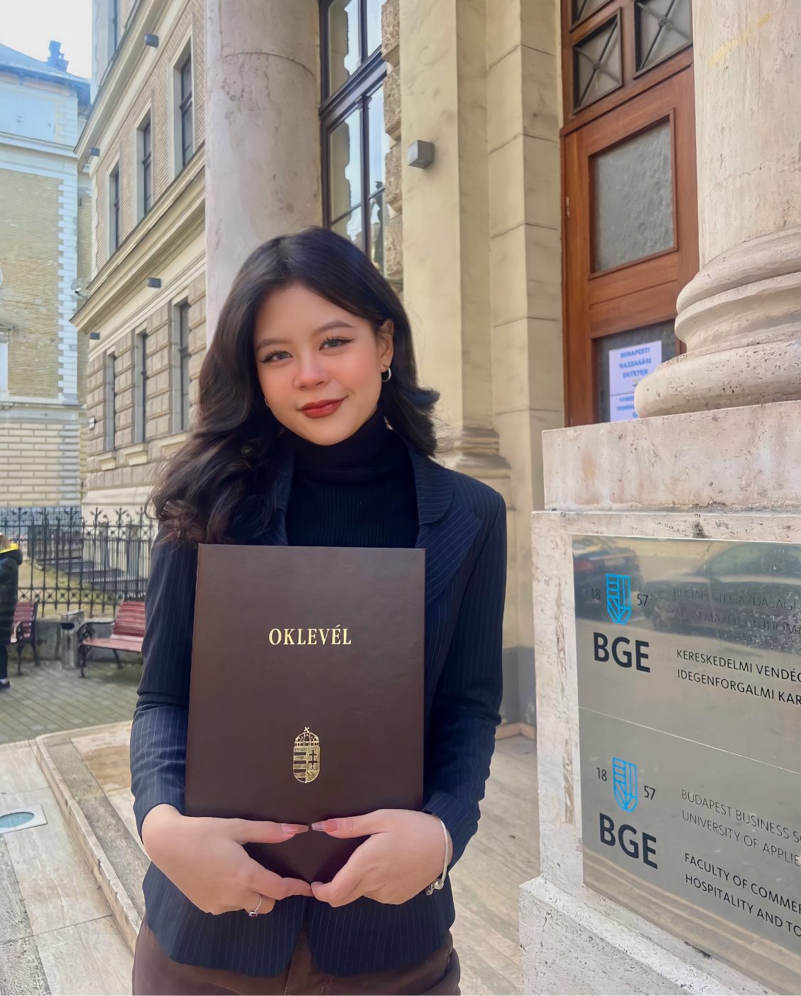 Helena holding her diploma on graduation day